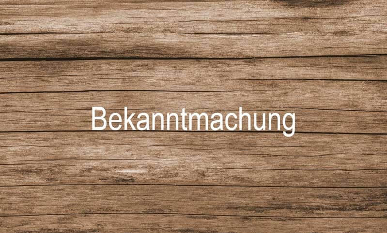 Zeigt den Schriftzug "Bekanntmachung" auf Holz